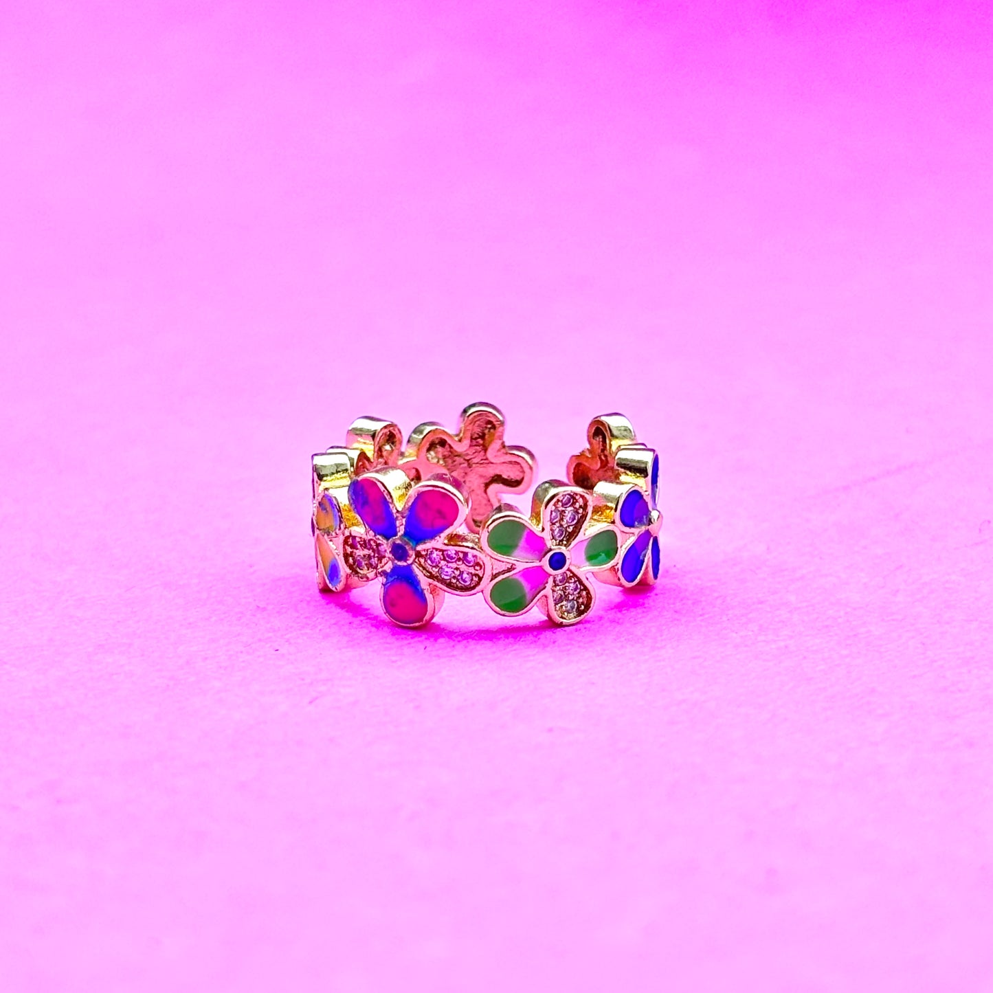 Colorful flower-shaped ring on a pink background