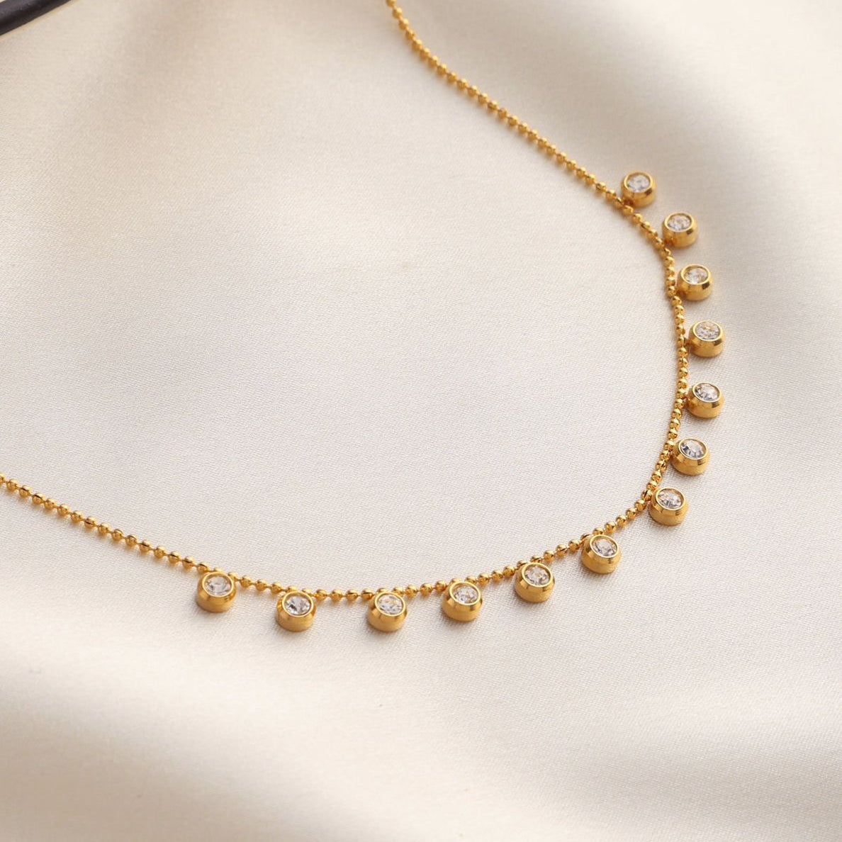 Gold necklace with small diamonds on a beige background