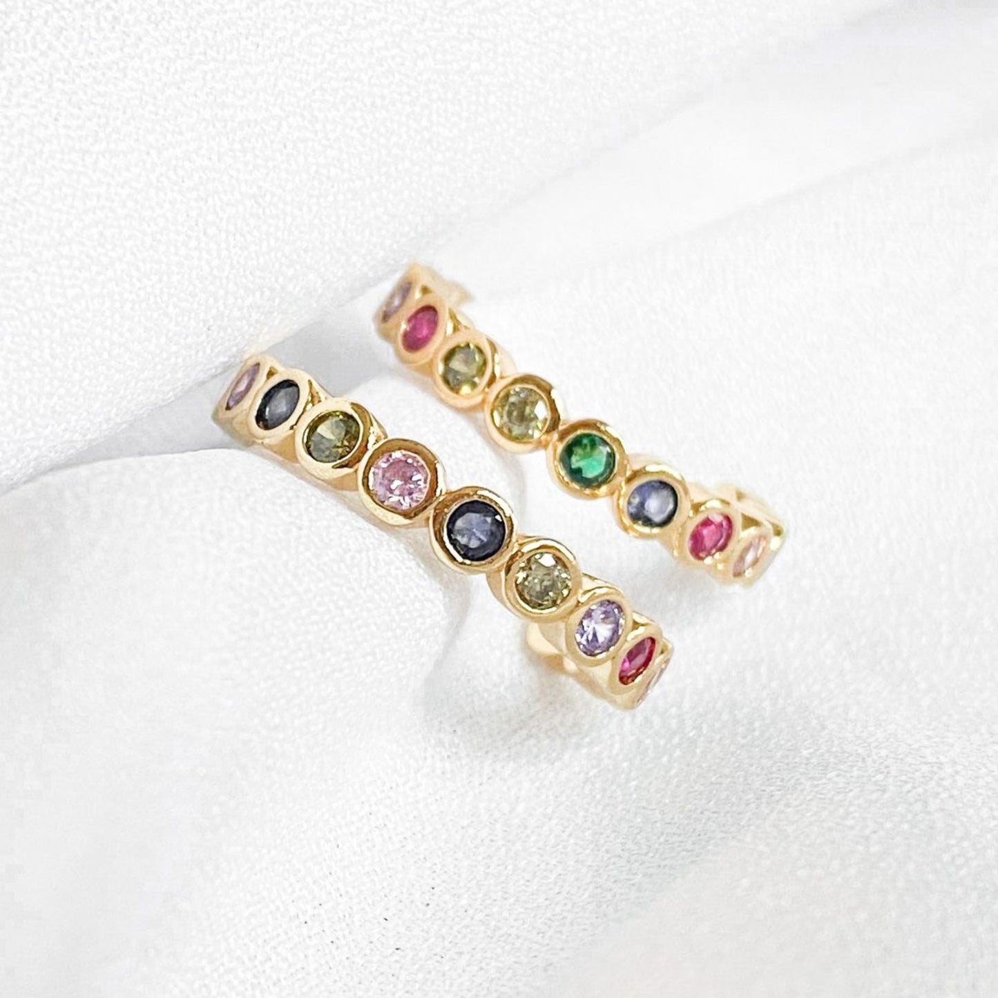 Gold rings with multicolored gemstones on a white background