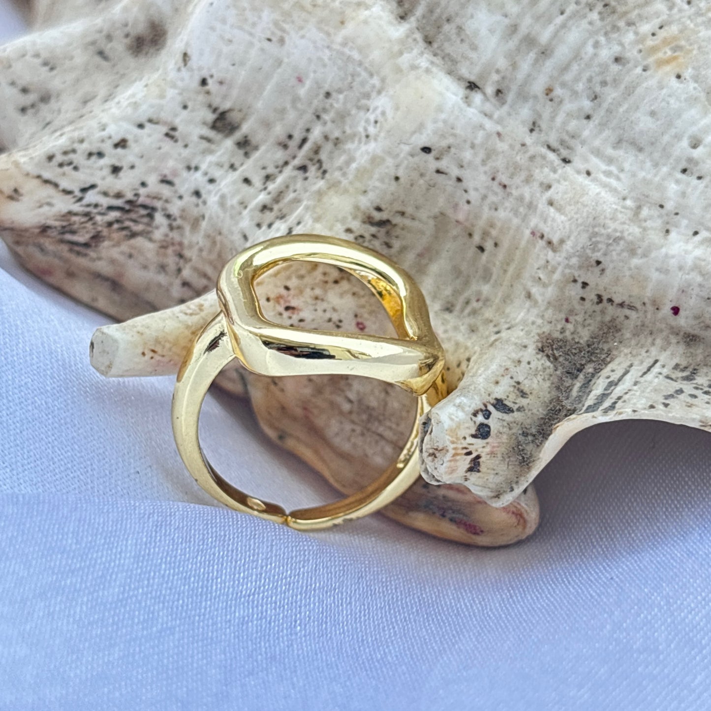Gold ring on a seashell with a light blue background