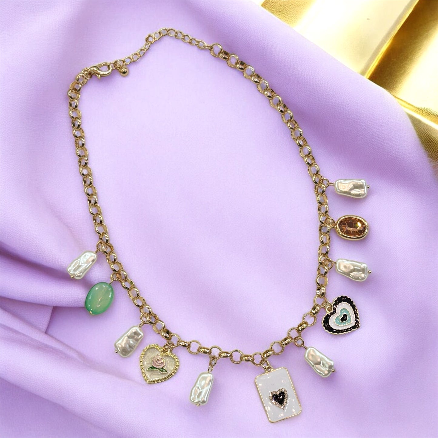 An 18K gold plated charm necklace with various charms including coins and pendants displayed on a mannequin.