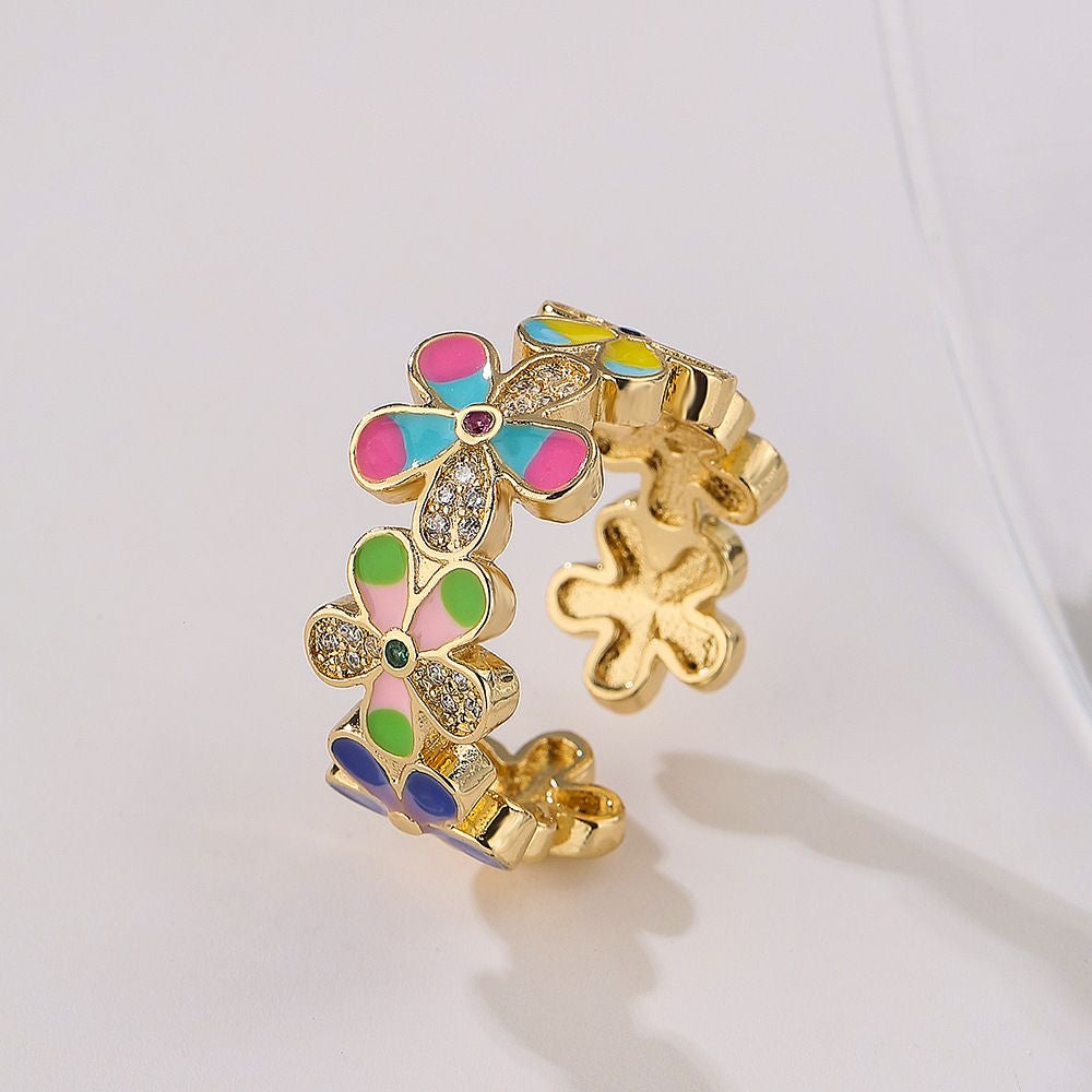 Gold colored ring with colorful flower shaped cuttings on white background