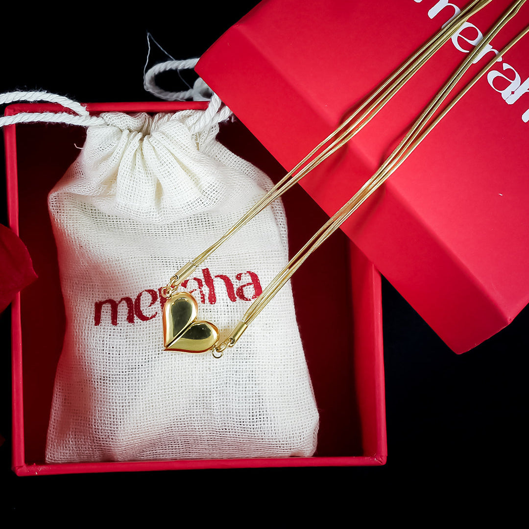 An 18k gold plated heart-shaped necklace with a magnetic closure, presented in a red box with a white drawstring bag, displaying the brand name 'Meraha'.