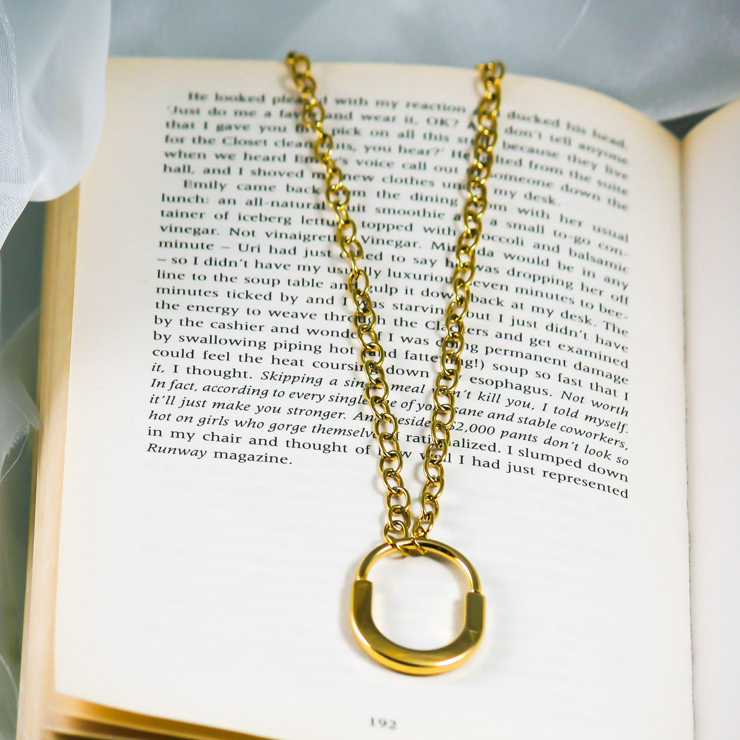 gold plated chain with a big lock loop pendant displayed on a book