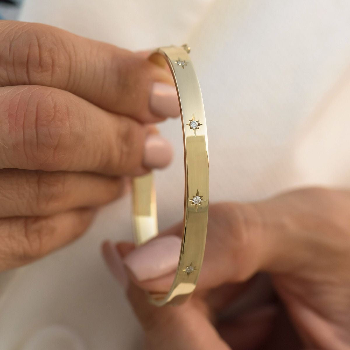 An 18k gold plated bracelet with star-shaped studs, displayed in hands