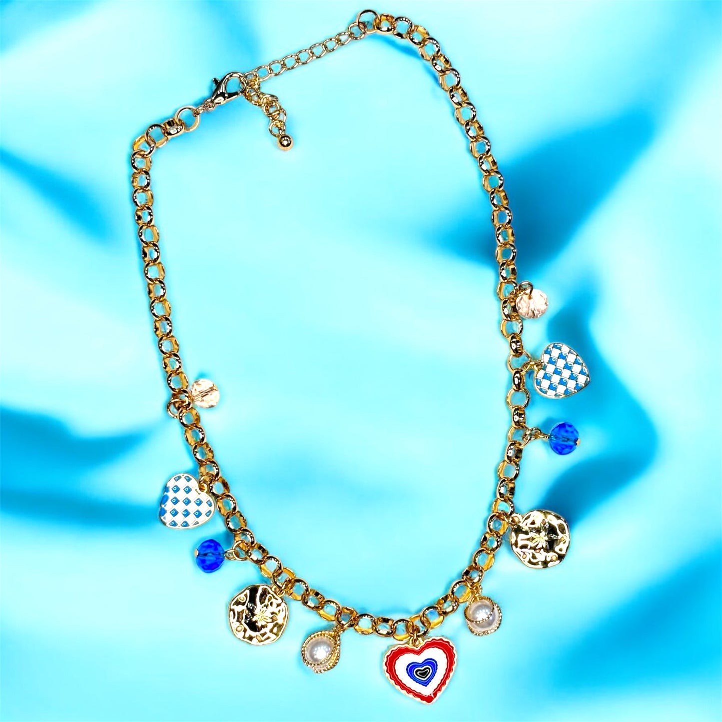 An 18K gold plated charm necklace with various charms including coins and pendants displayed on a mannequin.