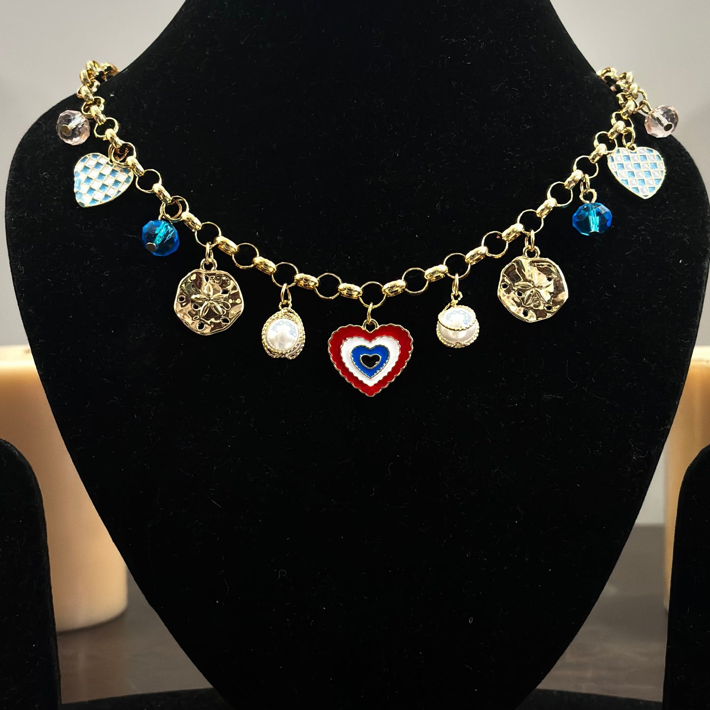 An 18K gold plated charm necklace with various charms including coins and pendants displayed on a mannequin.