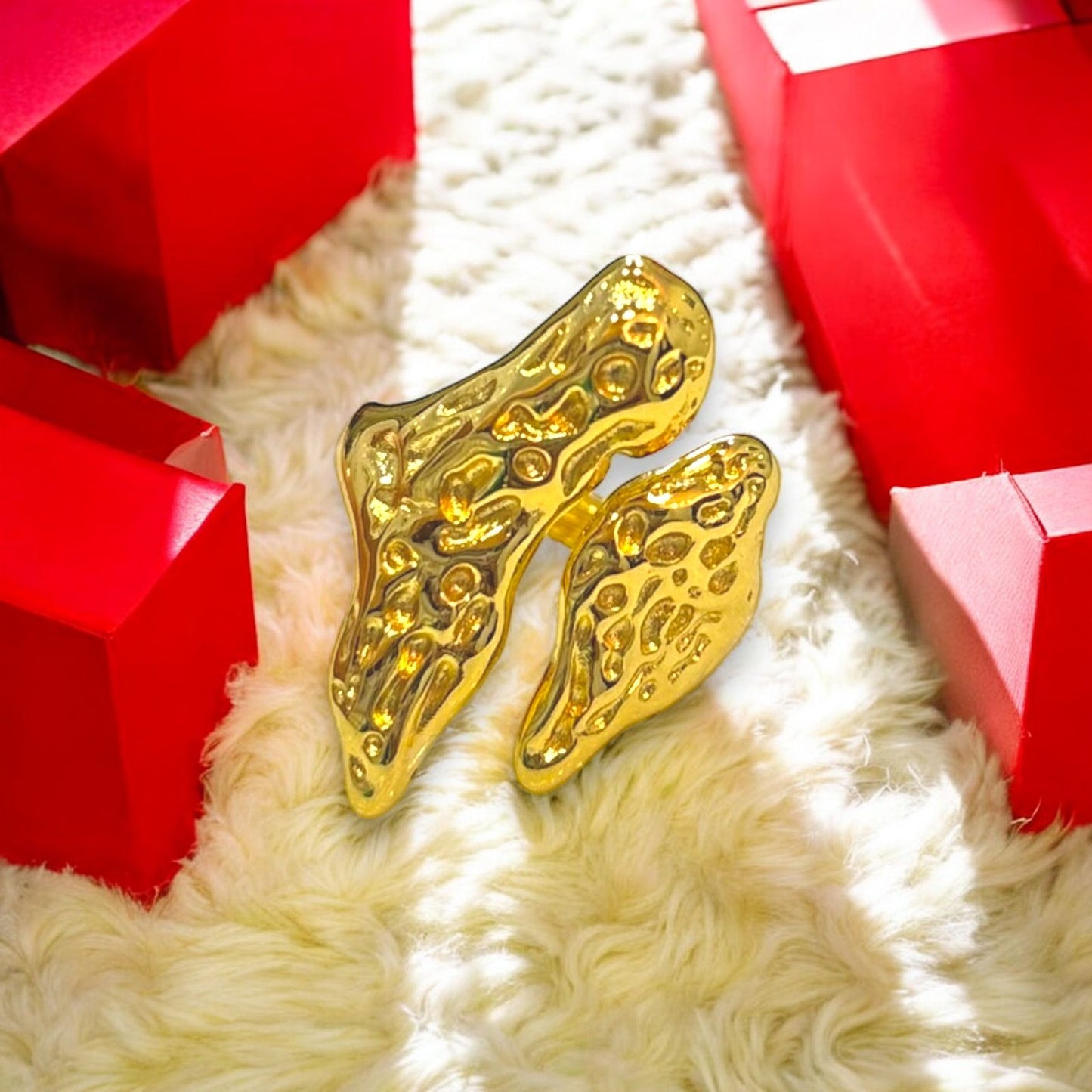 gold plated ring in abstract form with texture on it showcased on white fur background