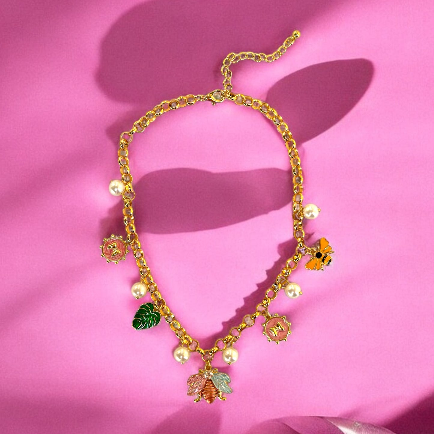 An 18K gold plated charm necklace with various charms including coins and pendants displayed on a mannequin.