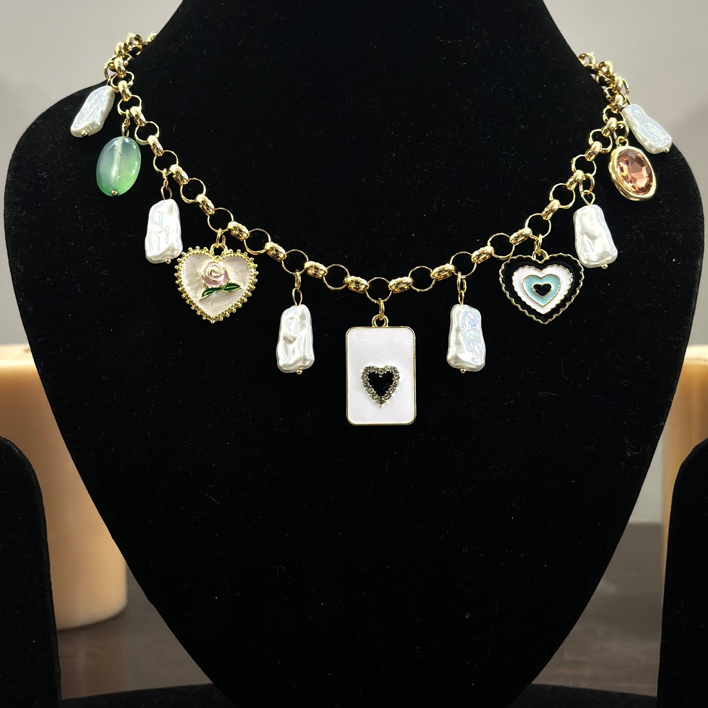 An 18K gold plated charm necklace with various charms including coins and pendants displayed on a mannequin.