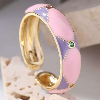 Ring with gold band and pink and purple gradient on a neutral background