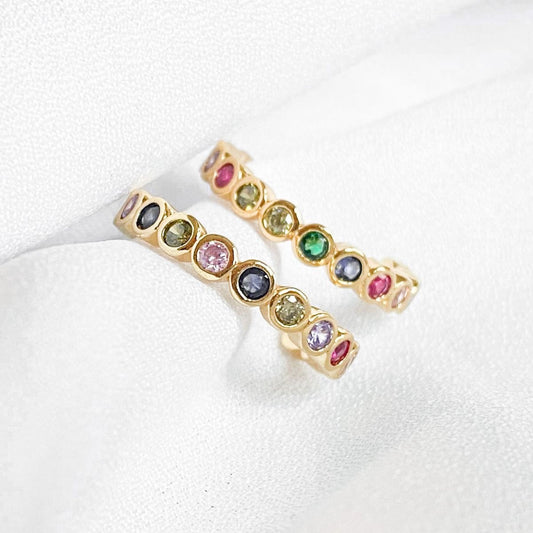 Gold rings with multicolored gemstones on a white background