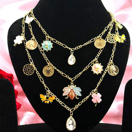 An 18K gold plated charm necklace with multiple chains and various charms including coins and pendants displayed on a mannequin.