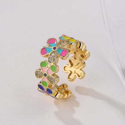 Gold colored ring with colorful flower shaped cuttings on white background