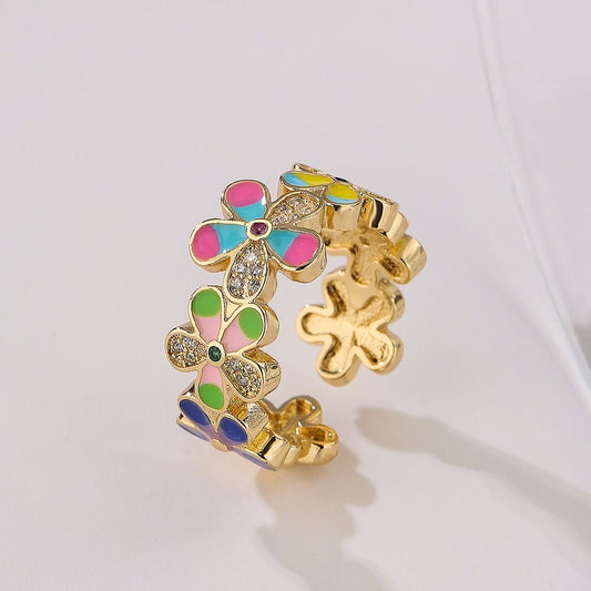 Gold colored ring with colorful flower shaped cuttings on white background
