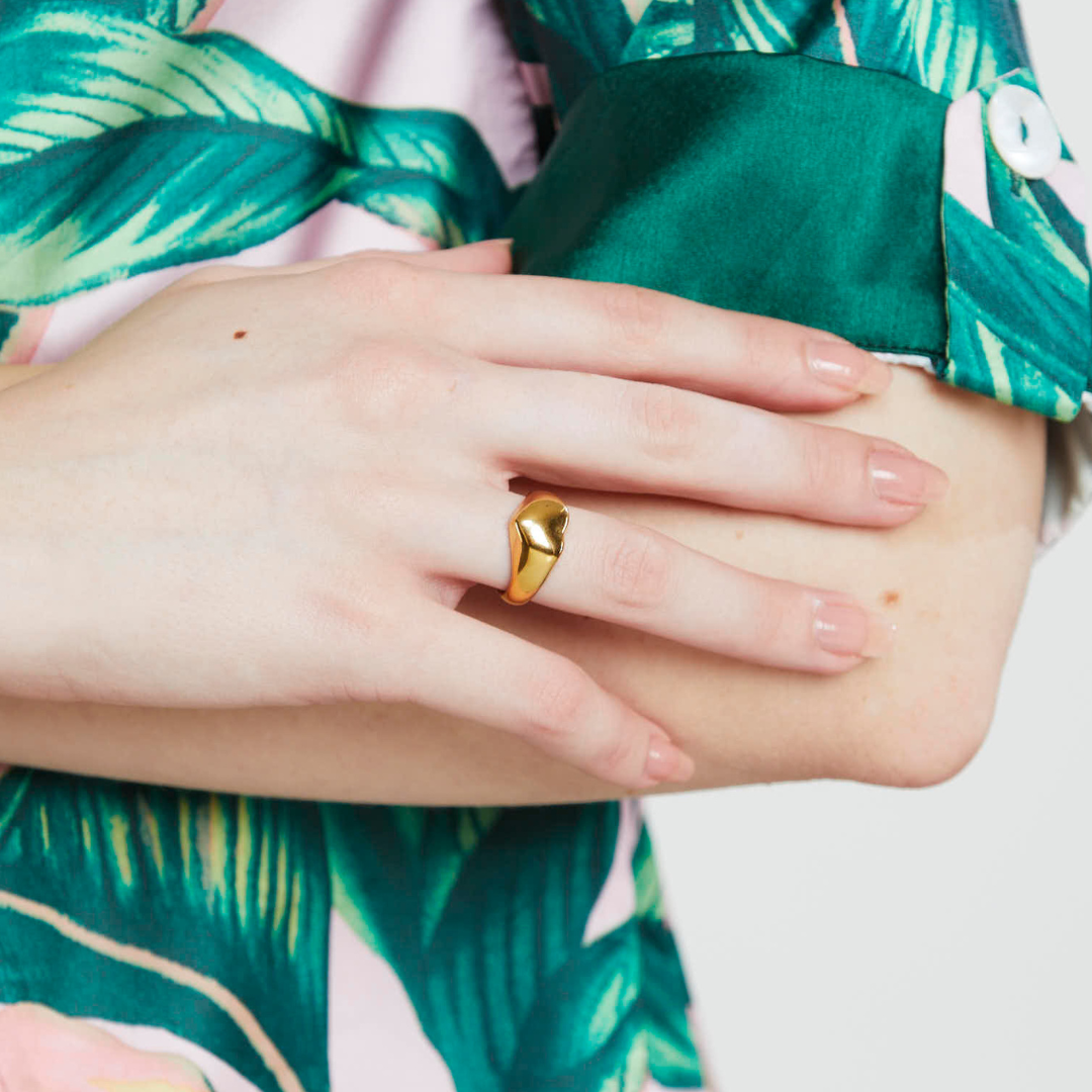 gold plated heart shaped ring displayed on a models hand 