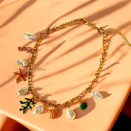 An 18K gold plated charm necklace with various charms including coins and pendants displayed on a mannequin.