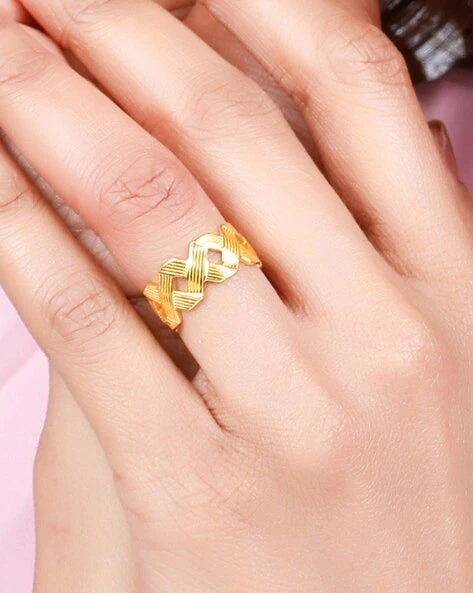 A gold-plated band ring with a criss-cross design on hands