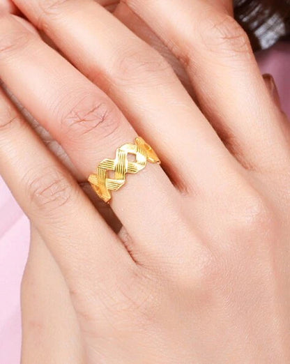 A gold-plated band ring with a criss-cross design on hands